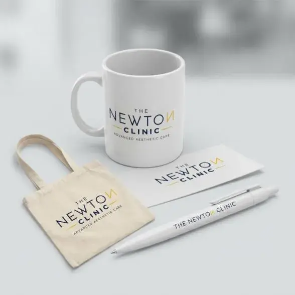 The Newton Clinic branded merchandise: mug, tote bag, pen, and card