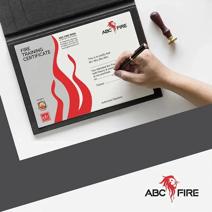ABC Fire - Fire Training Certificate being signed with a pen, red flame motif on left, company seal at right