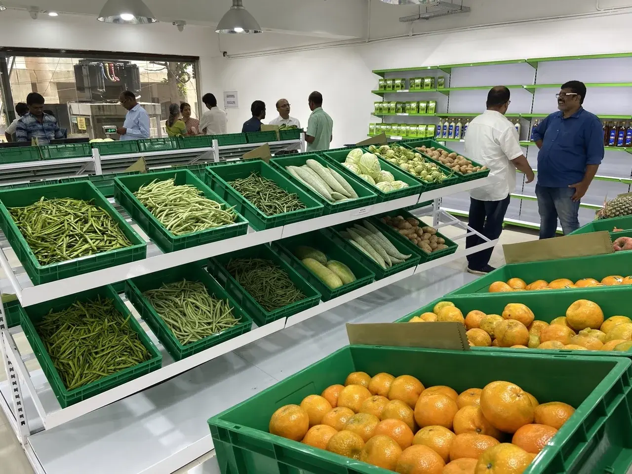 Maasilla store interior - fresh produce in branded green crates, customers browsing on opening day
